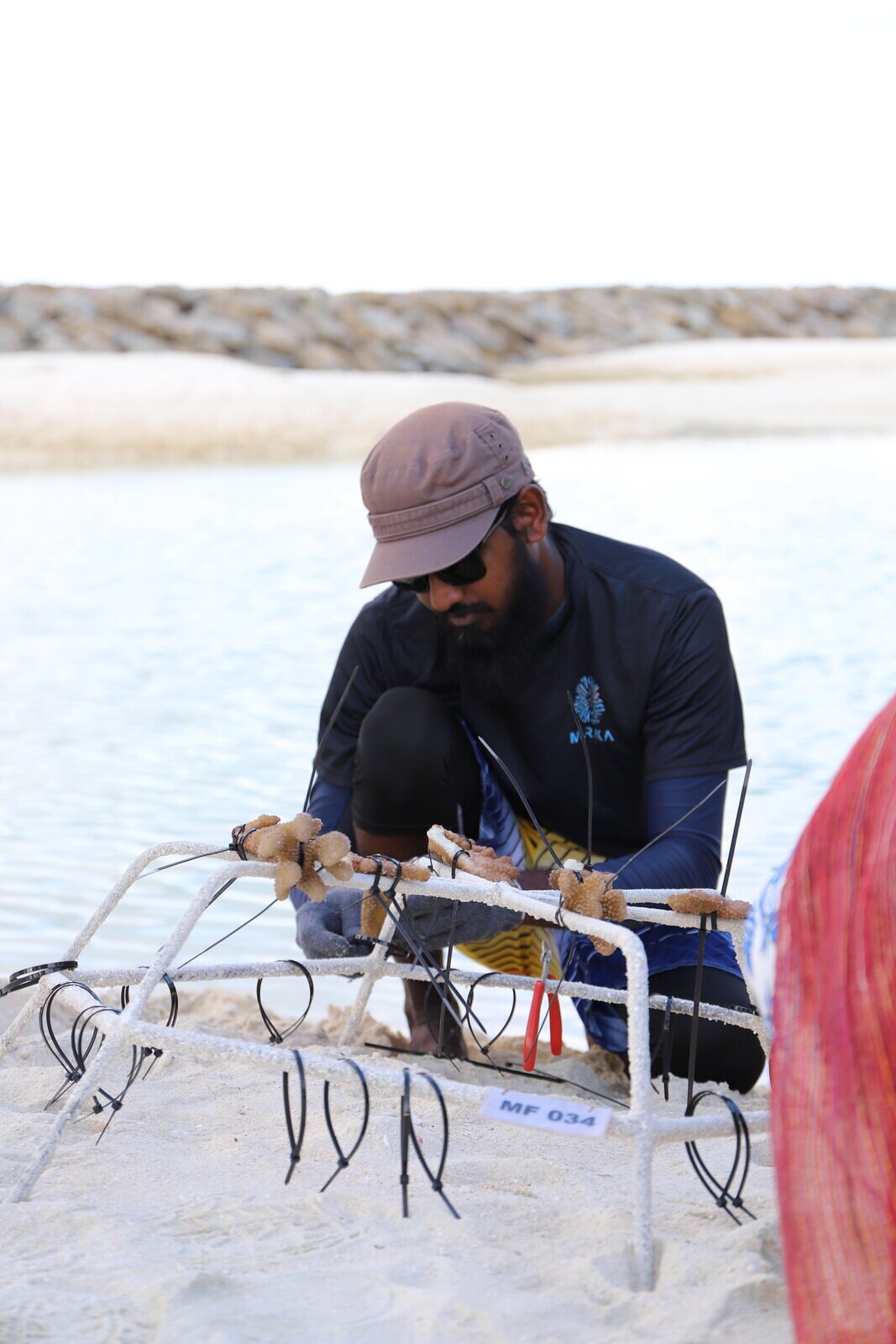 Muraka Farm team member preparing a coral restoration frame for the Dharavandhoo Muraka Project