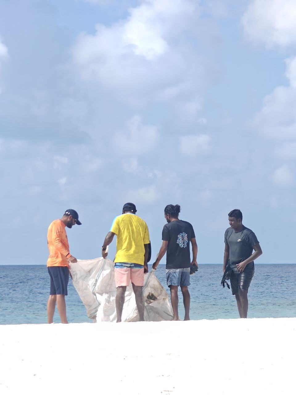 Community volunteers carrying collected waste beside the house reef