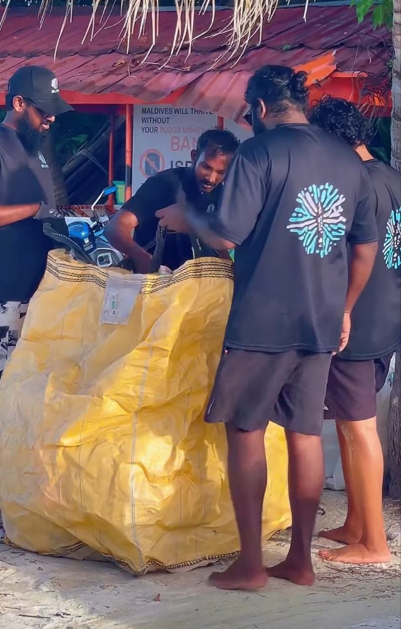 Muraka Farm members handling a collection bag during the Dharavandhoo beach clean-up